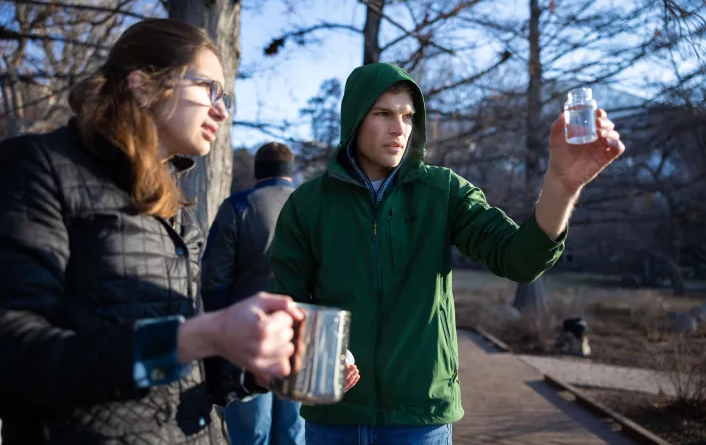 Os estudantes de engenharia da BYU, Bethany Parkinson e Owen Tolley, verificam a água após ter sido filtrada através de seu novo dispositivo, na lagoa de patos ao sul do campus em Provo, Utah, em 8 de fevereiro de 2022. Jaren Wilkey/BYU